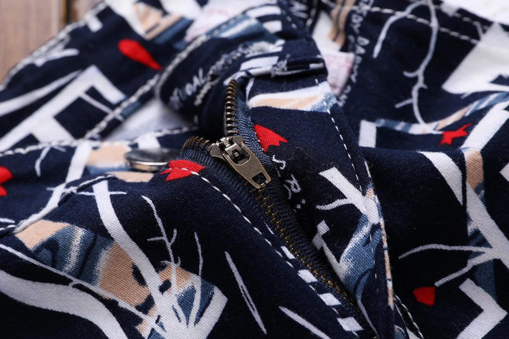 Close-up of a patterned fabric with a zipper, featuring geometric shapes and red accents.